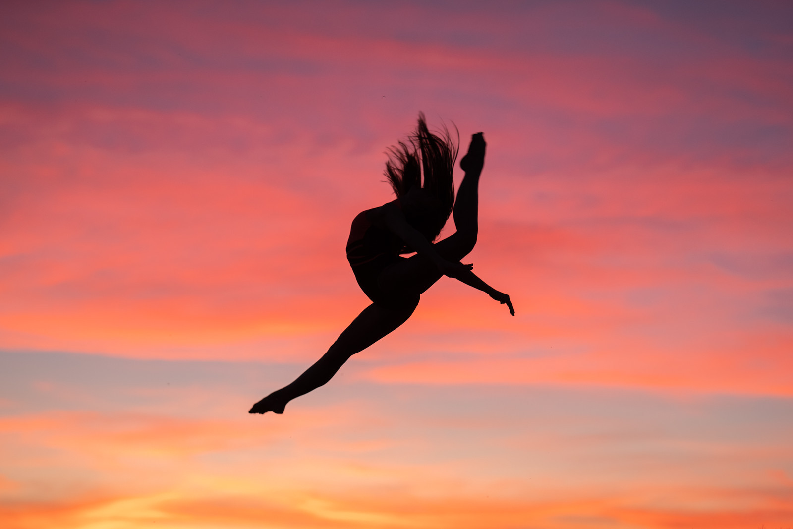 Dancer silhouette leaping against a pink and orange sunset sky, Spokane dance photography