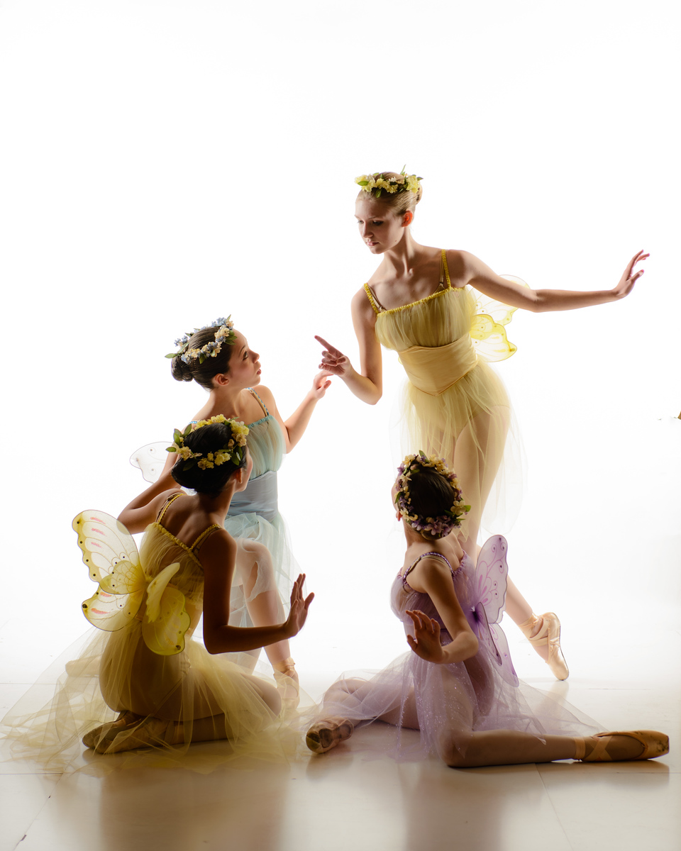 Four dancers in colorful fairy and butterfly costumes — yellow, blue, and purple — performing in a Spokane dance studio